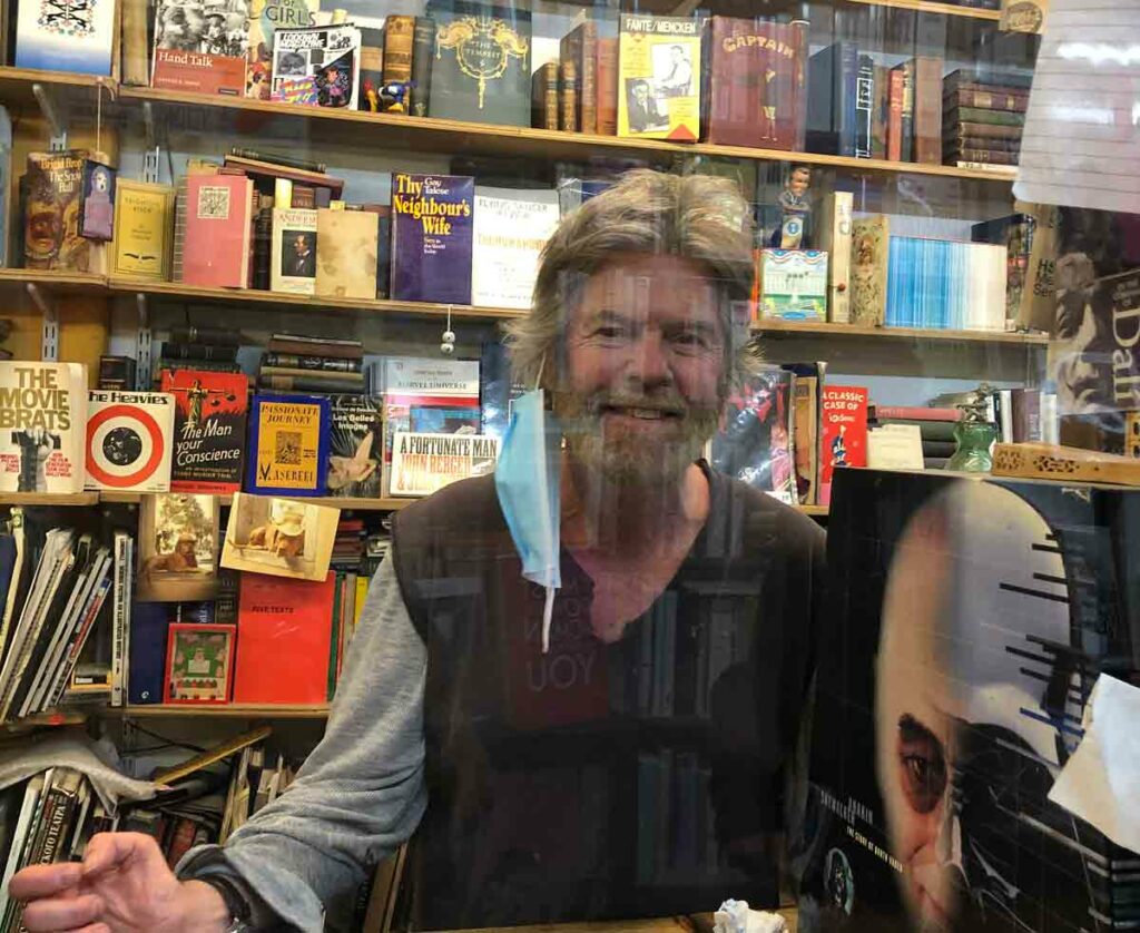 man in bookshop behind perspex screen
